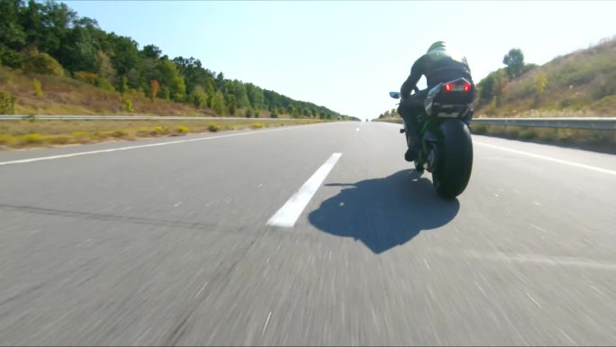 夏日，骑摩托车的人在公路旅行中驾驶摩托车。男子在高速公路上快速骑着现代运动摩托车。摩托车手在乡间小路