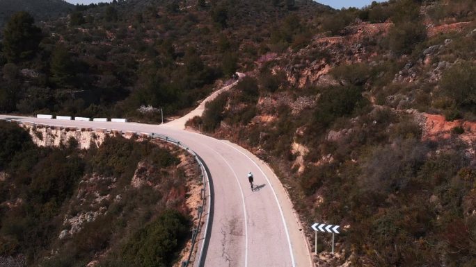 女自行车手在空旷的道路上上坡。在山上骑自行车的女人