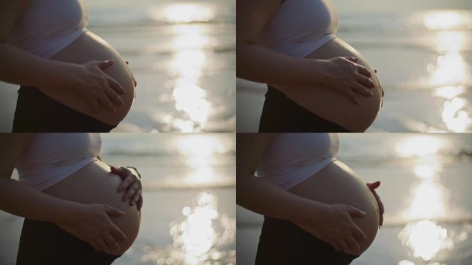 一个孕妇在海边的沙滩上抚摸着自己的肚子