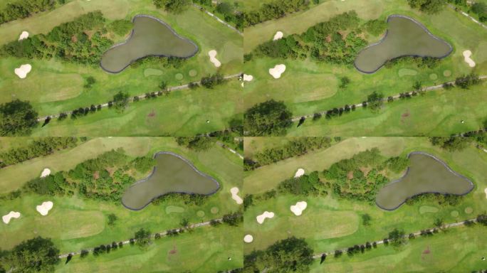 高空无人机拍摄的高尔夫球场水上危险。无人机飞过高尔夫球杆。池塘中间是绿油油的草地。4K无人机拍摄。