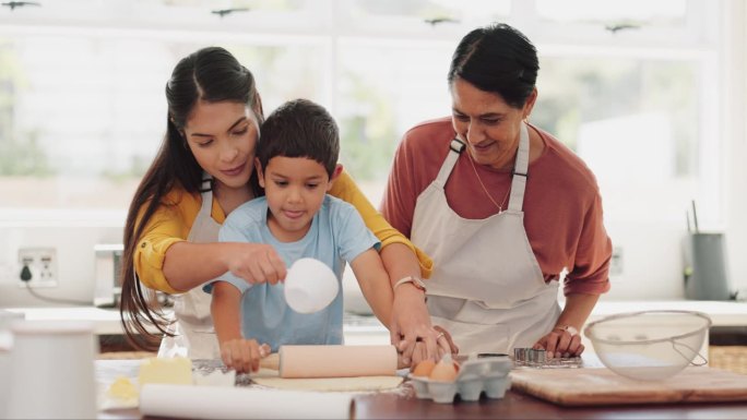 孩子，在厨房里和妈妈、奶奶一起学习做饭，用滚筒擀面。孩子，教育和烘焙，妈妈和奶奶教男孩，团结和幸福的