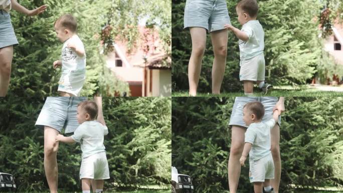 一个穿着t恤和短裤的小男孩在花园的草地上跳舞，旁边是他年轻的妈妈。