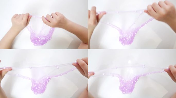 孩子的手在空中伸出亮紫色的黏液和大泡沫球。一个孩子在玩一个由粘液制成的充气泡沫玩具，一个时髦的液体玩