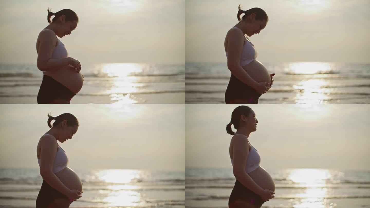 一个孕妇在海边的沙滩上抚摸着自己的肚子