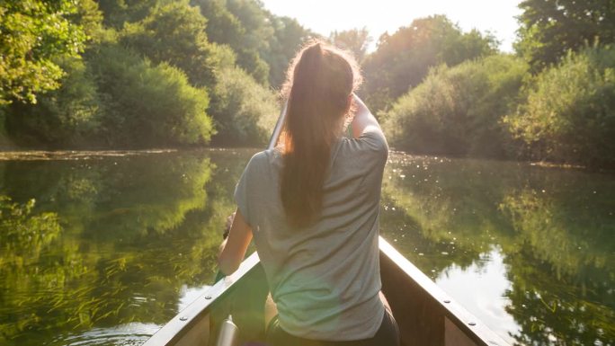 年轻的女旅行者在独木舟上欣赏风景优美的大自然