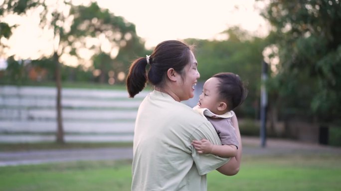 妈妈带着儿子在公园外面开心地笑着