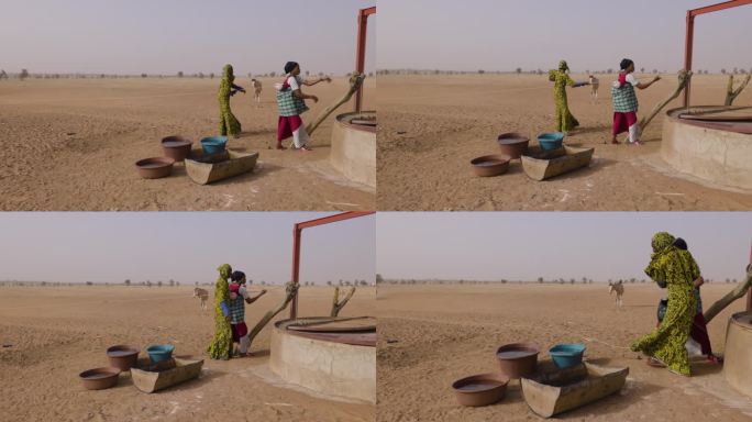 在贫瘠的塞内加尔撒哈拉沙漠萨赫勒地区，三个黑人妇女在驴子的帮助下从一口深井里打水。干旱，气候变化，沙