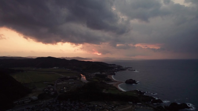 空中壮观的日落在日本海上海滩山天际线无人机云移动在京探戈上空的慢动作