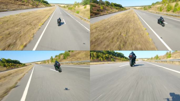 空中拍摄的男子骑着现代运动摩托车在高速公路上在夏天的一天。摩托车手在乡间公路上驾驶摩托车。有人在旅途