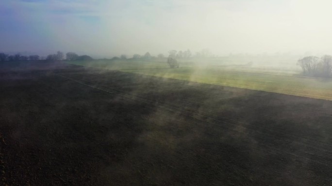 云吻着田野，在那里，绿色与刚犁过的土地相遇，被雾的轻声细语所拥抱