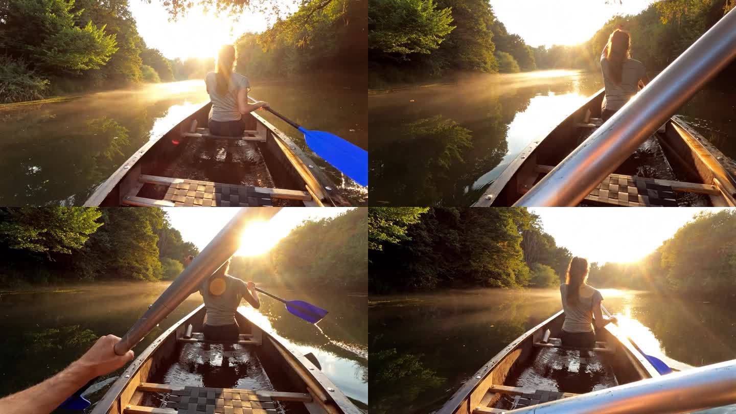 日落时分，一对情侣在雾蒙蒙的河上划独木舟