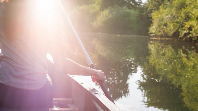 年轻女子在平静的绿色河流上的独木舟上放松
