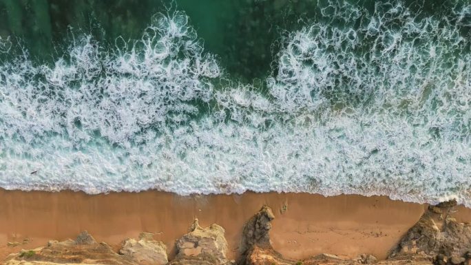 空中俯瞰的海洋冲浪和沙滩海岸与岩石。有泡沫的强大海浪