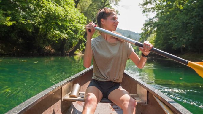 夏天，年轻的女旅行者在独木舟上欣赏风景优美的大自然