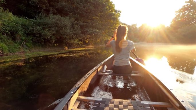 日落时分在郁郁葱葱的大自然中划独木舟探险