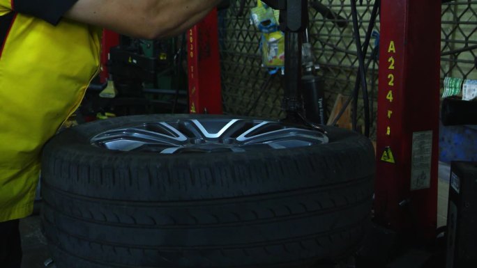 一名熟练的机械师正在从一台自动机器的车轮上卸下一个轮胎。