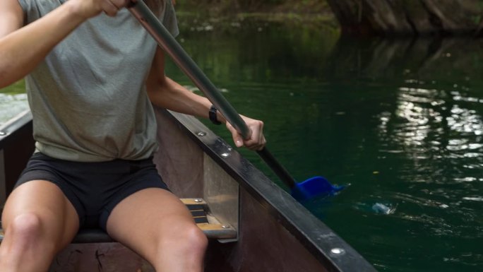 一个女人在独木舟上探索一条美丽的河流
