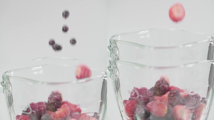 冰冻的红色和黑色覆盆子浆果滚下来的白色杯接近健康的有机天然水果