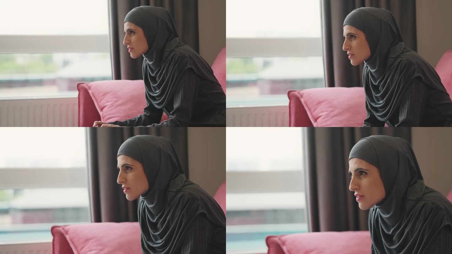 戴着头巾的穆斯林妇女在家里用操纵杆玩电子游戏，爱好