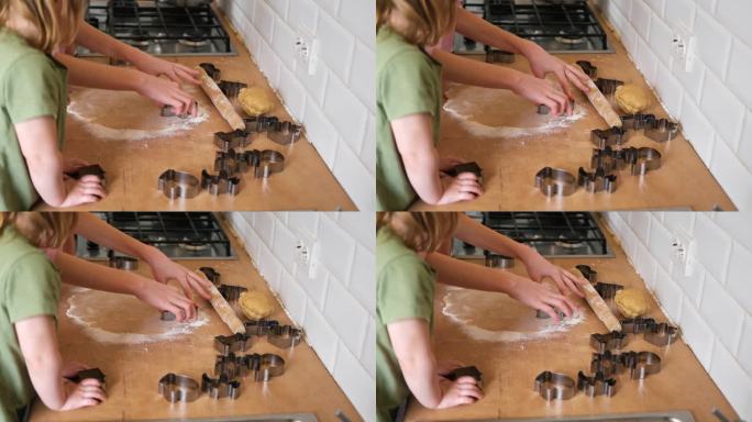 孩子们在厨房的台面上用木制擀面杖擀出饼干面团。金属烘烤模具。童年烘焙的乐趣，家庭传统，自制美食。兄弟