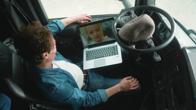 卡车司机和他的小儿子在笔记本电脑上进行视频通话，积极的反应和快乐