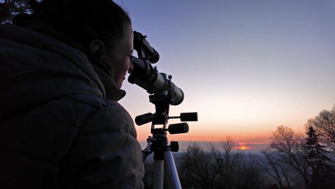 业余天文学家用望远镜和特殊的太阳滤光片观察日食和太阳。