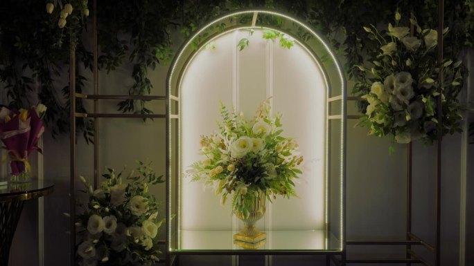 豪华的白花装饰，安排在一个单一的花束在一个金色的花瓶设置在一个发光的拱廊，跟踪拍摄