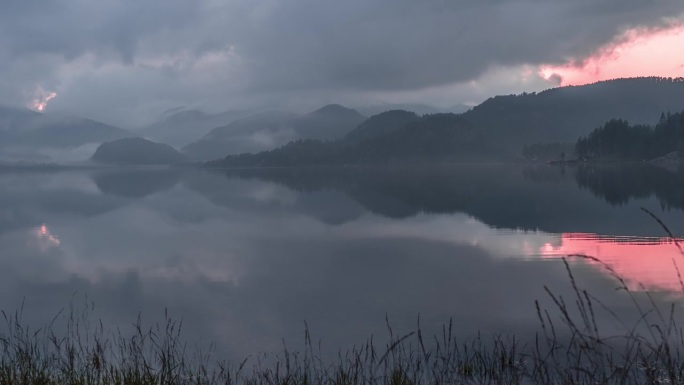 在平静如镜的湖面上，低低的云爬过落日的天空。一个延时视频。