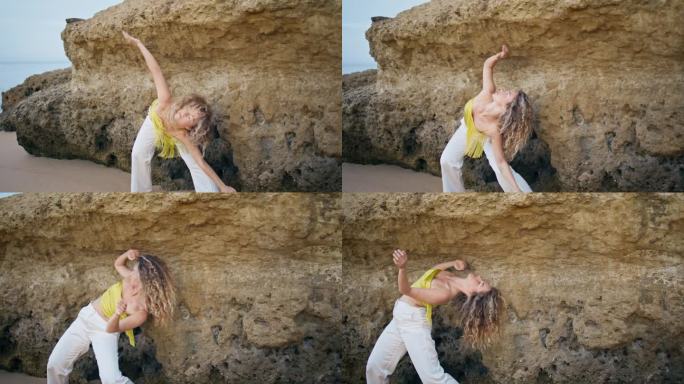 当代女孩在岩石岸边跳舞，身体弯曲灵活。优秀的舞者