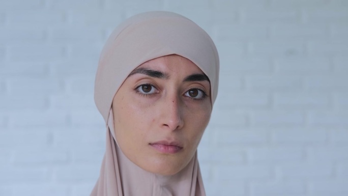 戴头巾的穆斯林妇女悲伤地看着镜头。优美的五官，坚定的目光，严肃的神情，传达着人的紧张状态。表情比语言