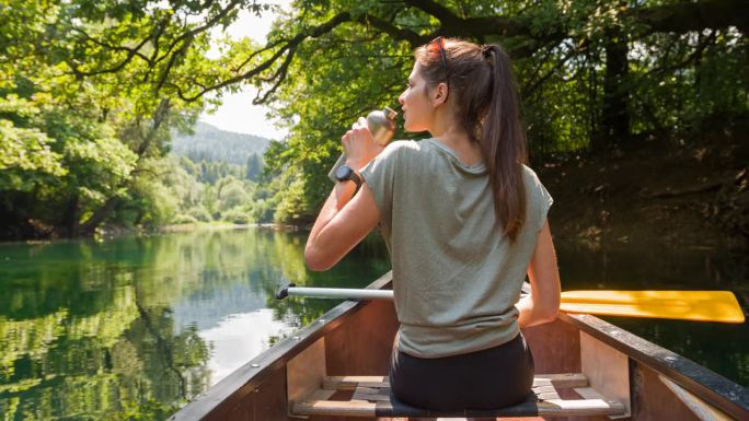 年轻女子在平静的河流上划着独木舟休息