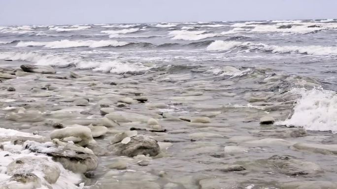 覆盖着冰雪的海滩。海面波涛汹涌，海浪拍击着海岸。现场荒凉而寒冷，没有生命或活动的迹象