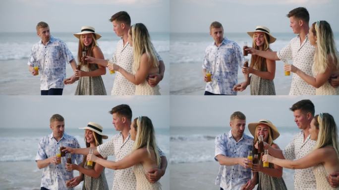 一群带着康普茶瓶子的男人和女人在阳光明媚的热带海滩上散步，喝酒，聊天，微笑。两对快乐的白人夫妇在海边