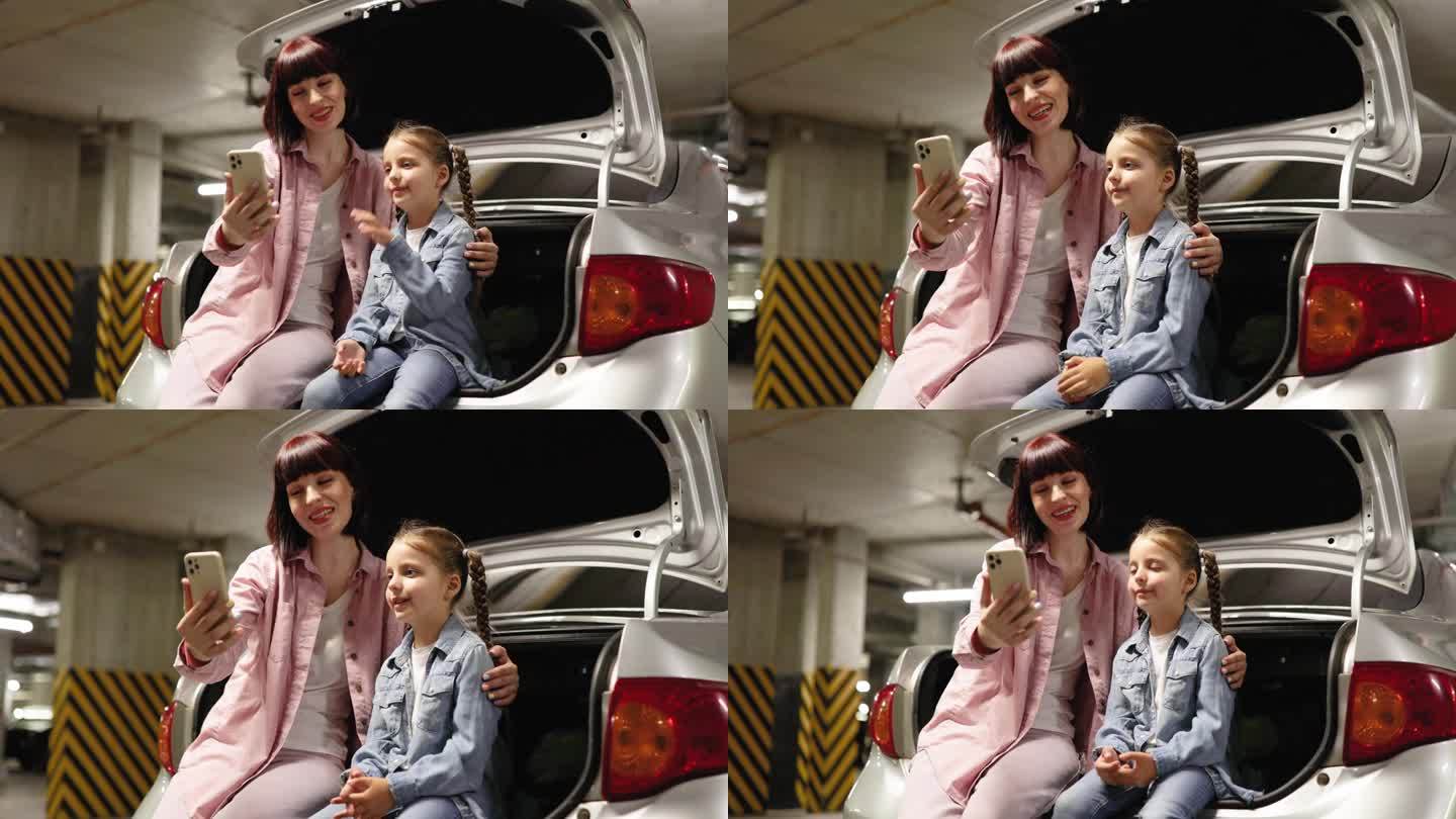 母女俩在地下停车场用智能手机自拍。