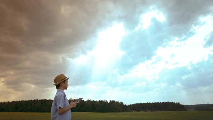 自然的探索者:男孩博物学家站在田野里玩平板电脑