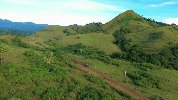 鸟瞰图，一辆4x4越野车在红色的越野赛道上穿过绿色的山丘