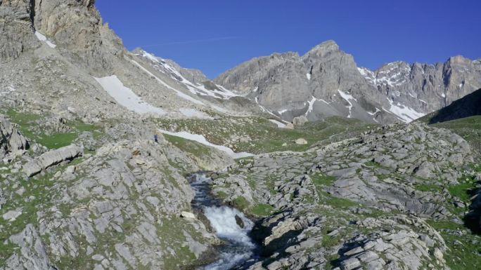 山涧流经岩石地形与山峰，卡斯卡塔迪斯特罗皮亚和拉戈涅拉在背景，阳光明媚的一天