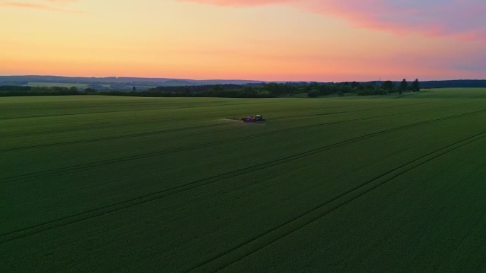 无人机空中交响乐:黄昏时，拖拉机在农业进步的挂毯上喷洒绿色的田野