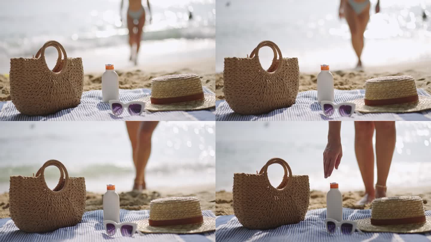 沙滩必需品放在毛巾，防晒瓶，防紫外线。人们走向大海，准备晒日光浴。夏日休闲配饰，帽子，墨镜，沙滩手提