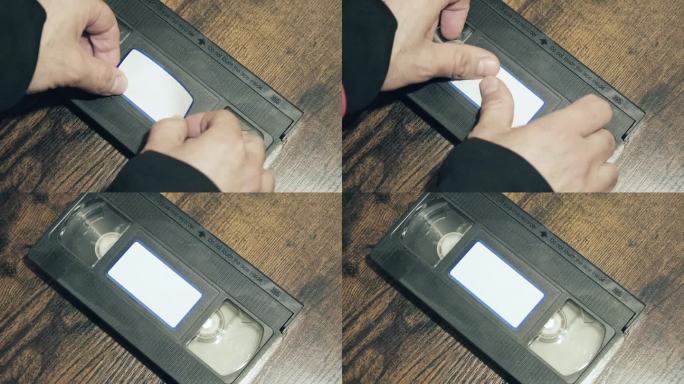 用手在老式录像带的正面贴上空白的标签。