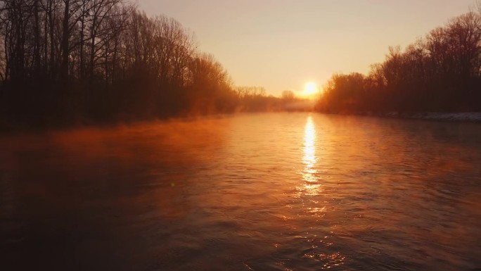 无人驾驶的阳光在穆尔河上跳舞，照亮了树木剪影中宁静的水面