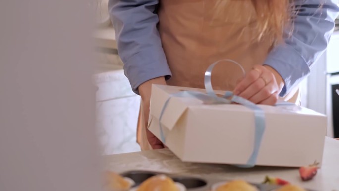 一位女糕点师正在把纸杯蛋糕装进盒子里。家庭烘焙，小生意，环保生产，无麸质，无糖，提倡健康饮食习惯。
