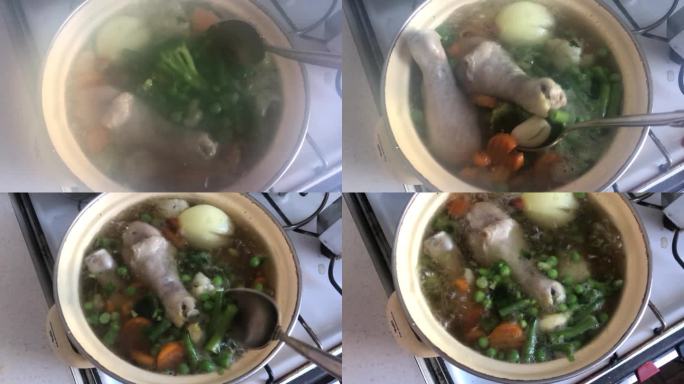 水平直从上面的视频鸡汤煮在一个老式炉子上的黄色平底锅。孩子的腿，胡萝卜，绿色和平，洋葱都看得见。一个