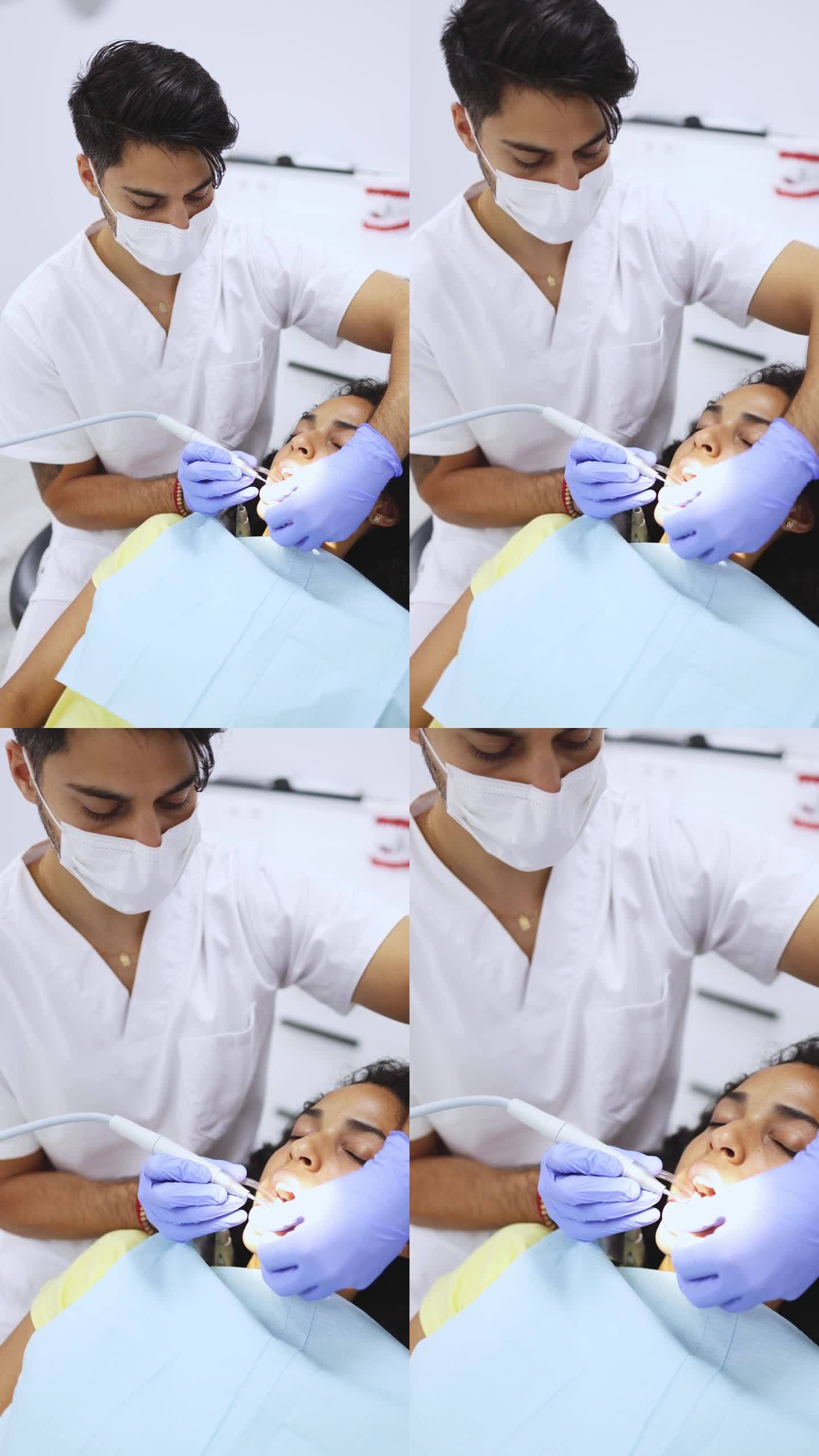 一个男性牙医在现代诊所用牙钻从年轻病人身上去除牙牙垢菌斑的垂直视频