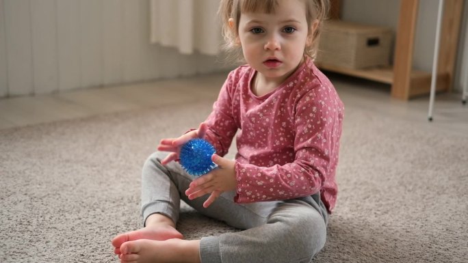可爱的女婴在玩有触觉的球形球。幼儿手玩感官按摩球。增强认知、生理过程。大脑发育。支持患有多动症、自闭