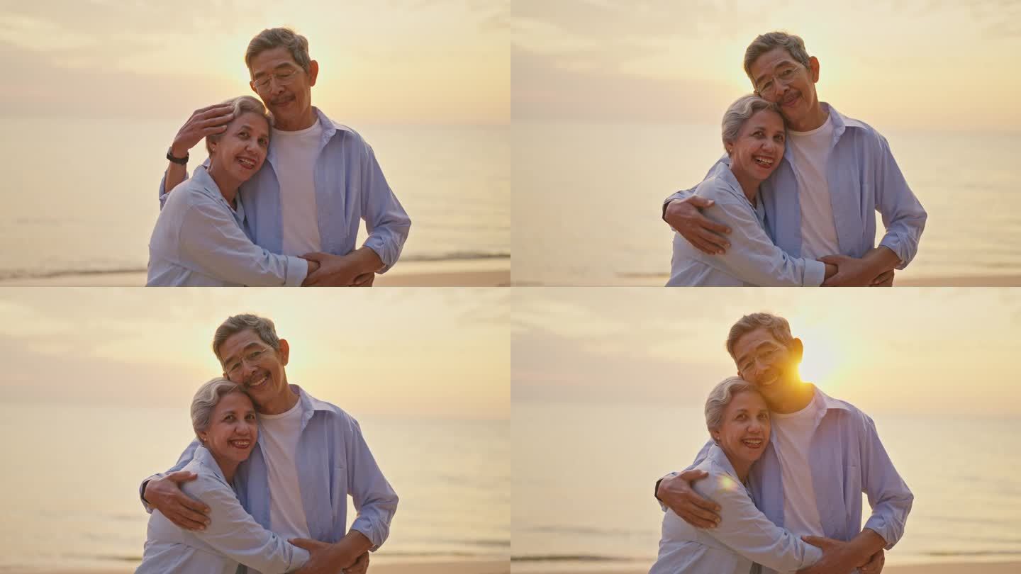 一对老年夫妇在日落时分在海滩上拥抱。