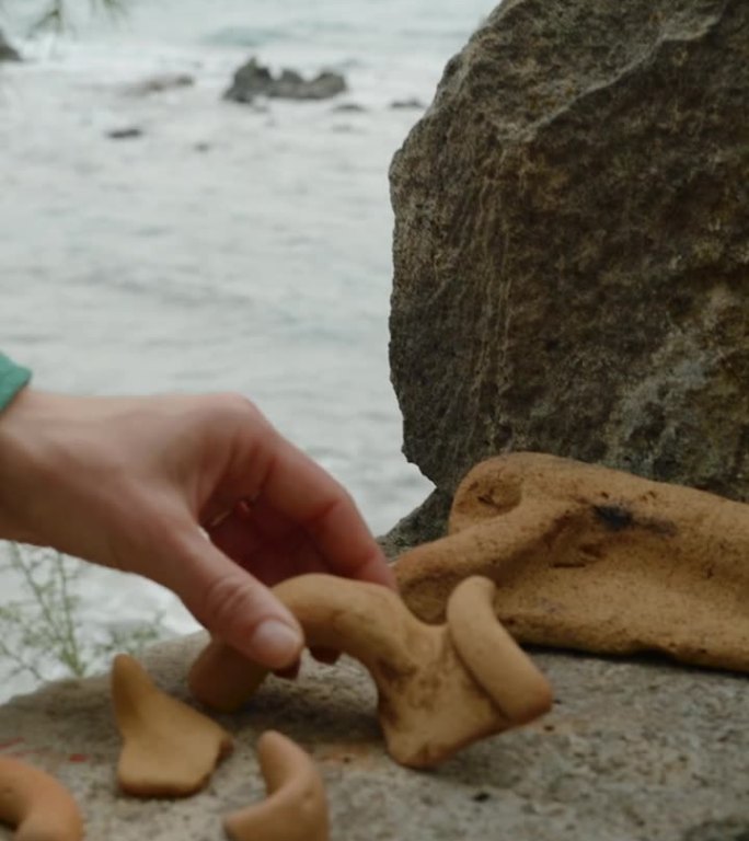 垂直视频。这个女人在海边悬崖上的一所老房子的废墟中探索，发现了古希腊粘土陶器的碎片。