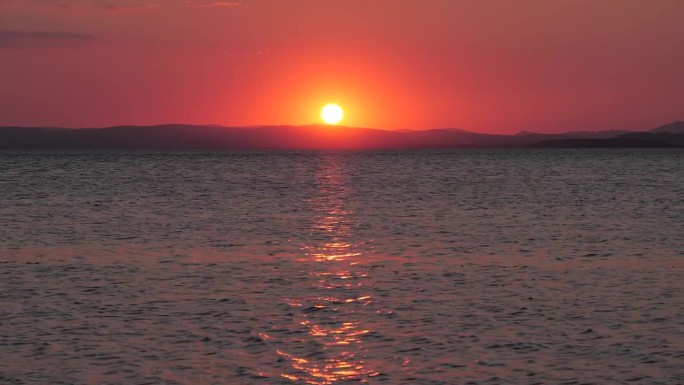 4K:海上金色的夕阳。英格兰兰开夏郡的莫克姆湾面向湖区山丘。库存视频剪辑镜头。