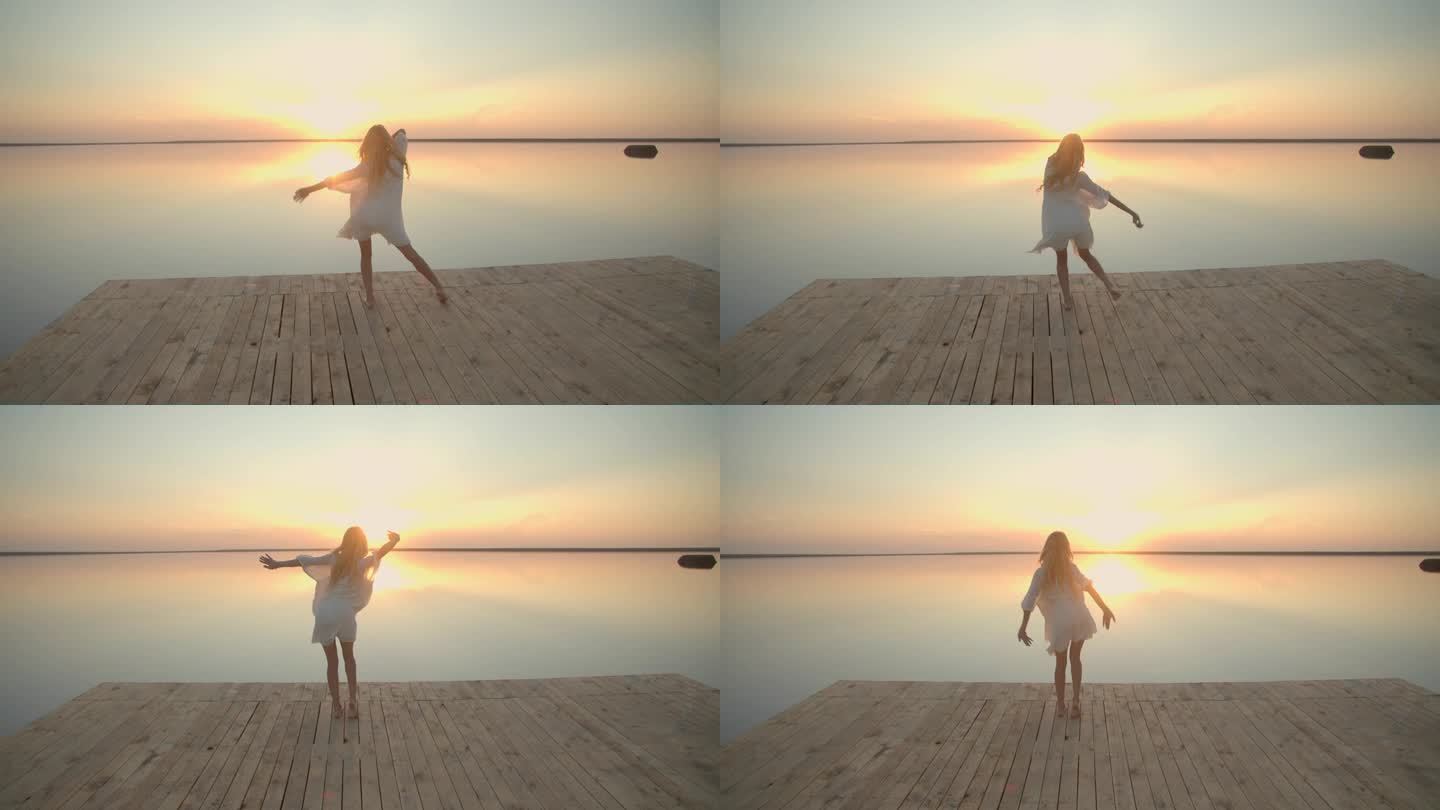 身穿白裙的金发女子在湖边的木码头上跳舞，夕阳西下
