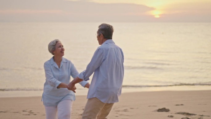 夕阳下，一对快乐的老年夫妇在海滩上跳舞。